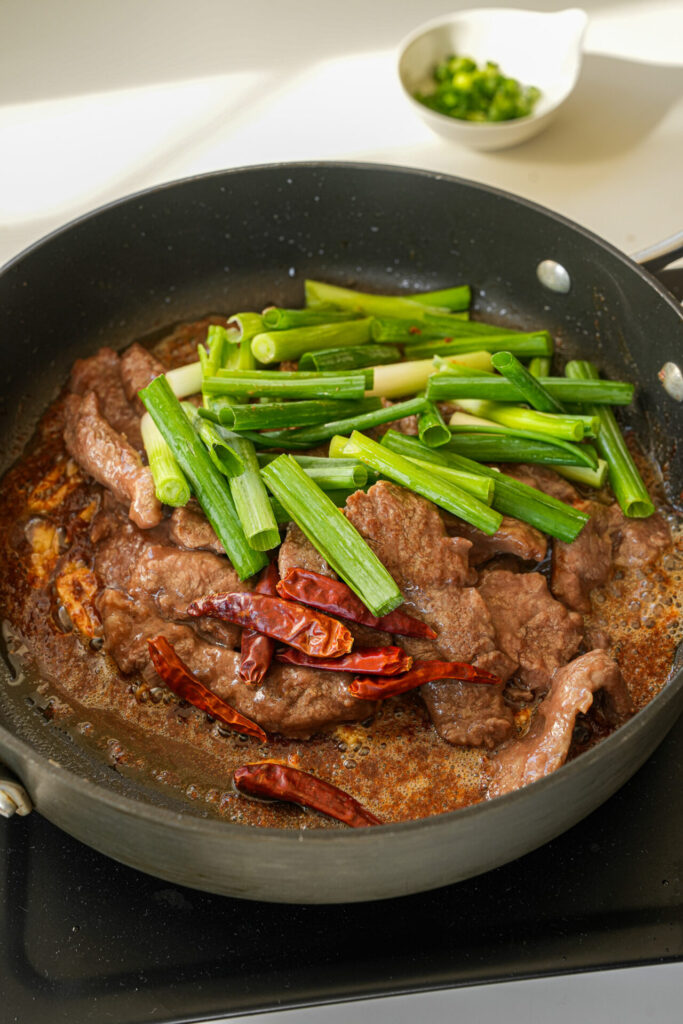 Add beef scallion and dried chilies to sacha beef stir fry