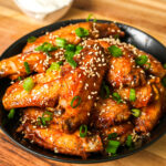 air fryer sweet and sour chicken wings garnished with green onions and sesame seeds