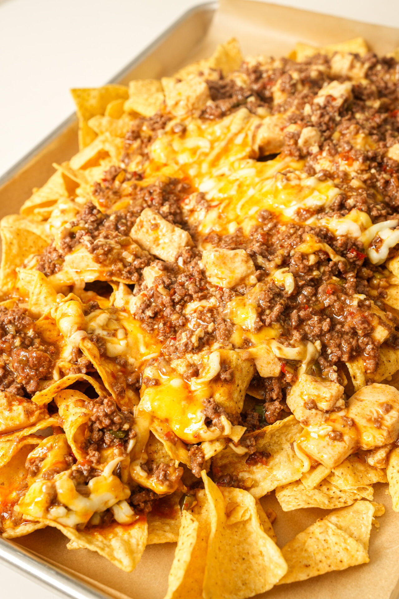 pour mapo tofu and cheese mixture onto a tray of tortilla chips